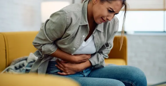 une femme tient le bas de ventre de douleur