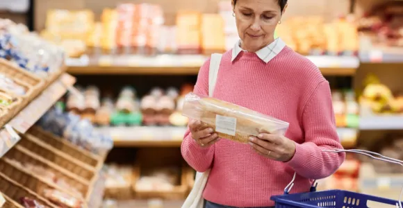 une femme consulte l'étiquette d'un pain en magasin