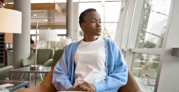 une jeune fille d'origine africaine assise pensive dans un bureau