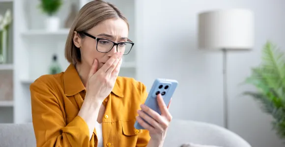 Une jeune femme apeurée devant ce qui s'affiche sur son smartphone.