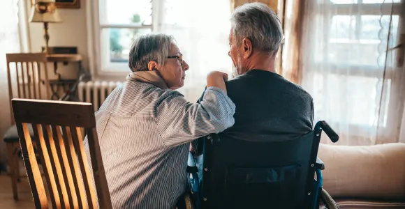 un monsieur en fauteuil roulant converse avec la personne qui l'aide