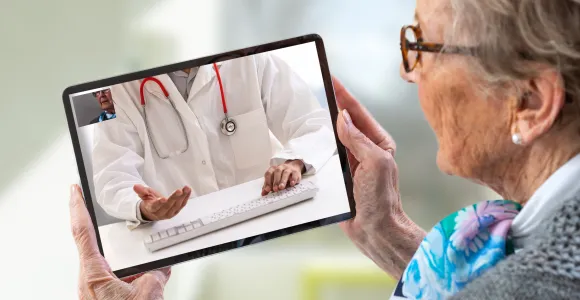 une dame âgée consulte son médecin en ligne sur tablette
