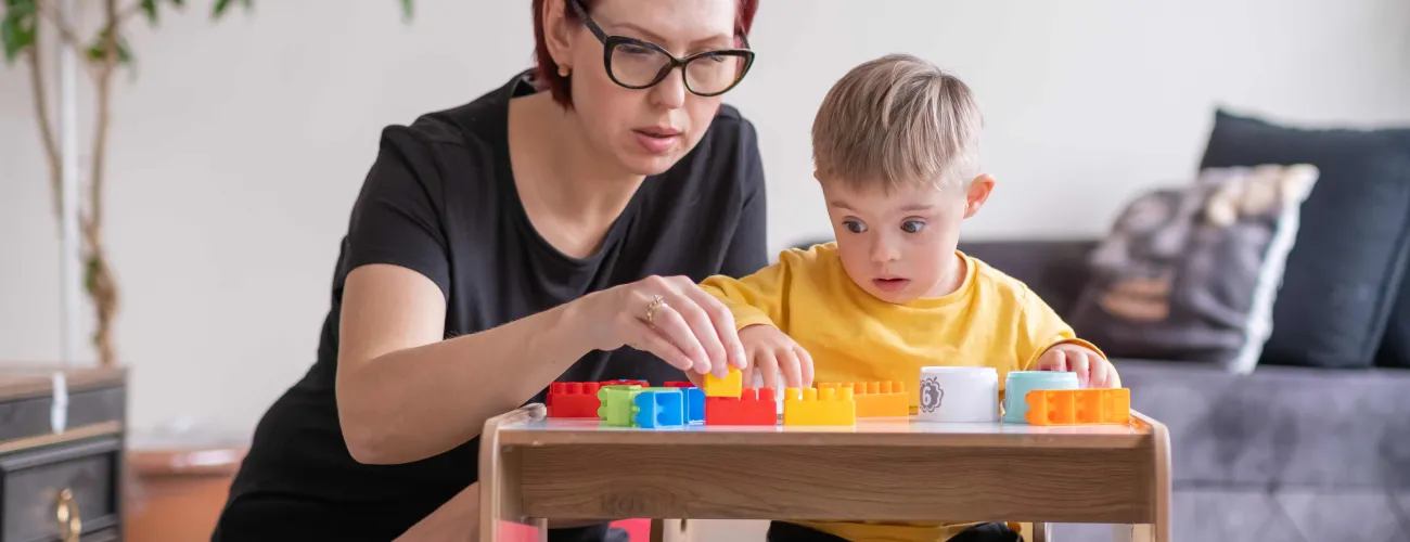 Une maman joue aux cubes avec son enfant porteur d'une trisomie