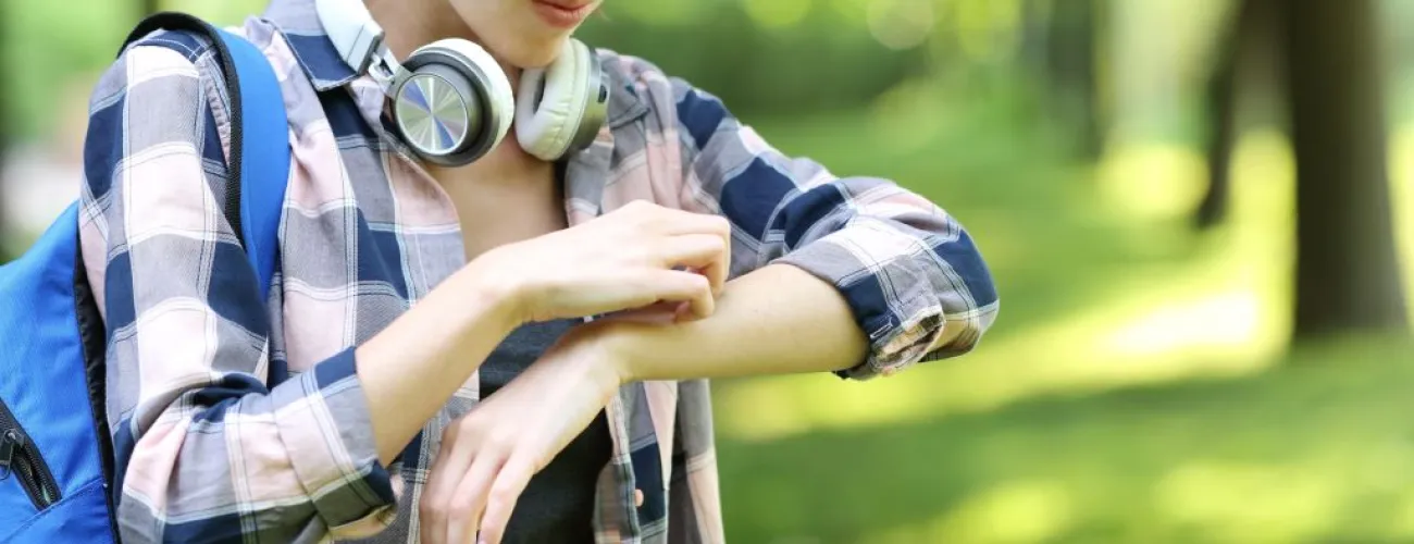 Jeune femme se grattant l'avant-bras gauche en faisant une tête contrariée