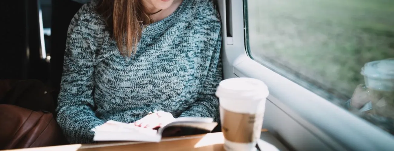Femme assise dans un train qui lit un livre