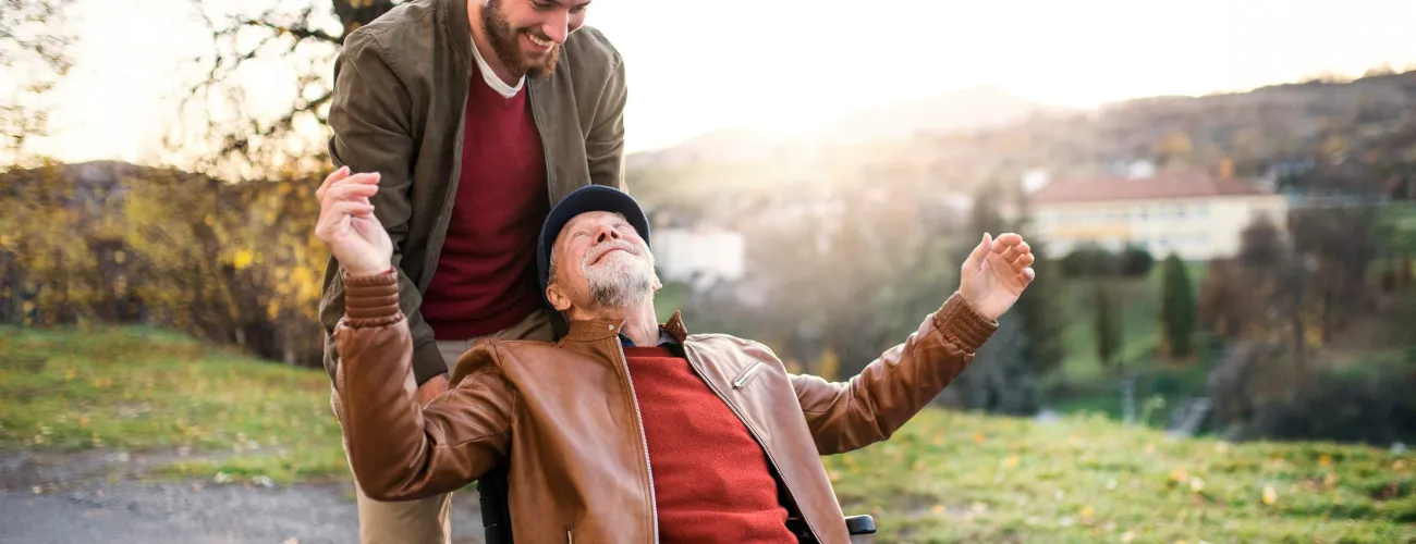 Un jeune homme pousse un vieil homme en fauteuil roulant