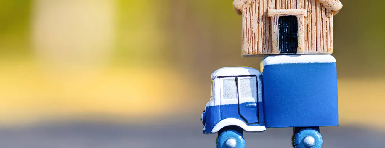 Un petit camion en bois transporte une petite maison en bois