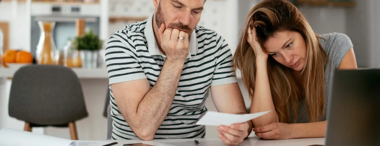 Un couple est dépité en regardant des documents derrière leur ordinateur