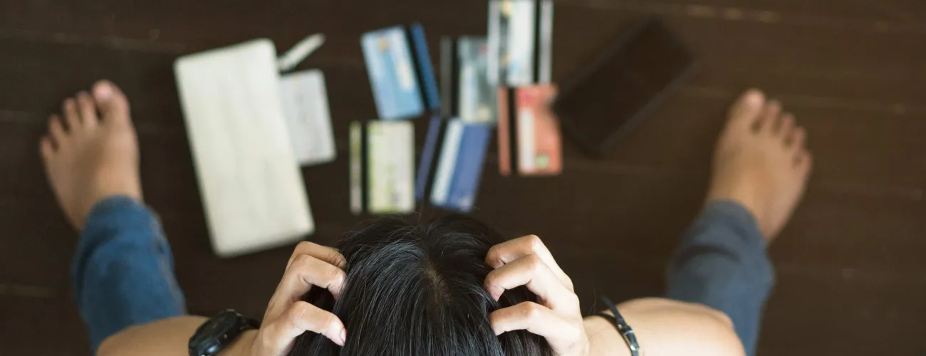 Un femme se tient la tête en détresse face à plusieurs cartes de crédit
