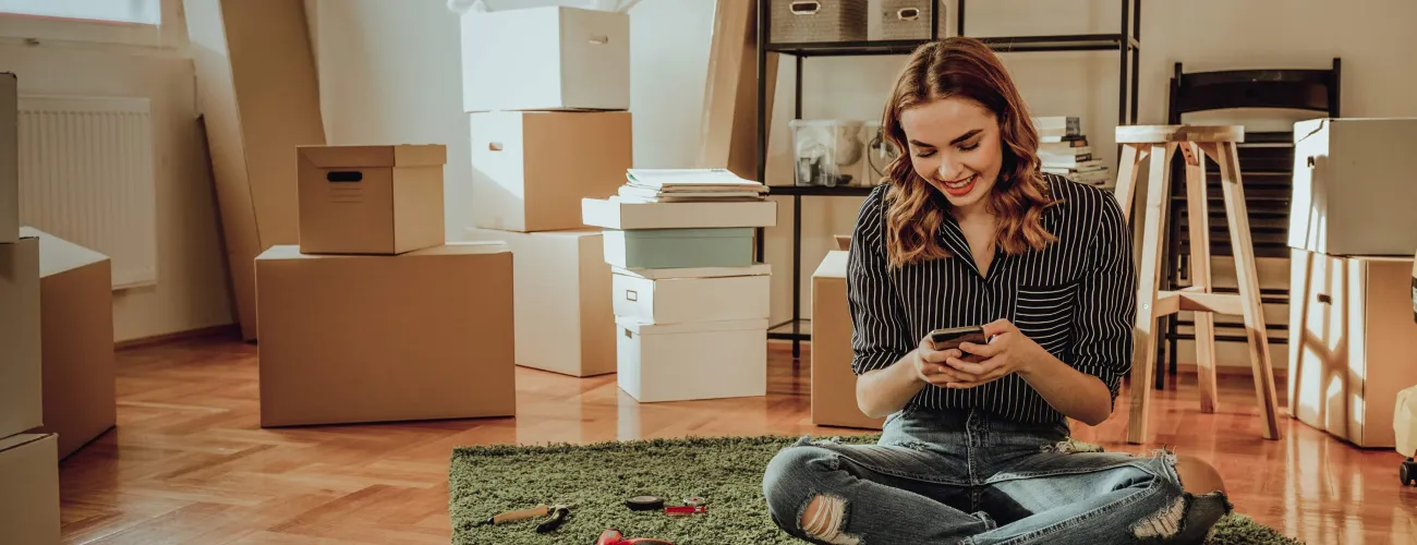 Une jeune femme sur son smartphone est en plein déménagement
