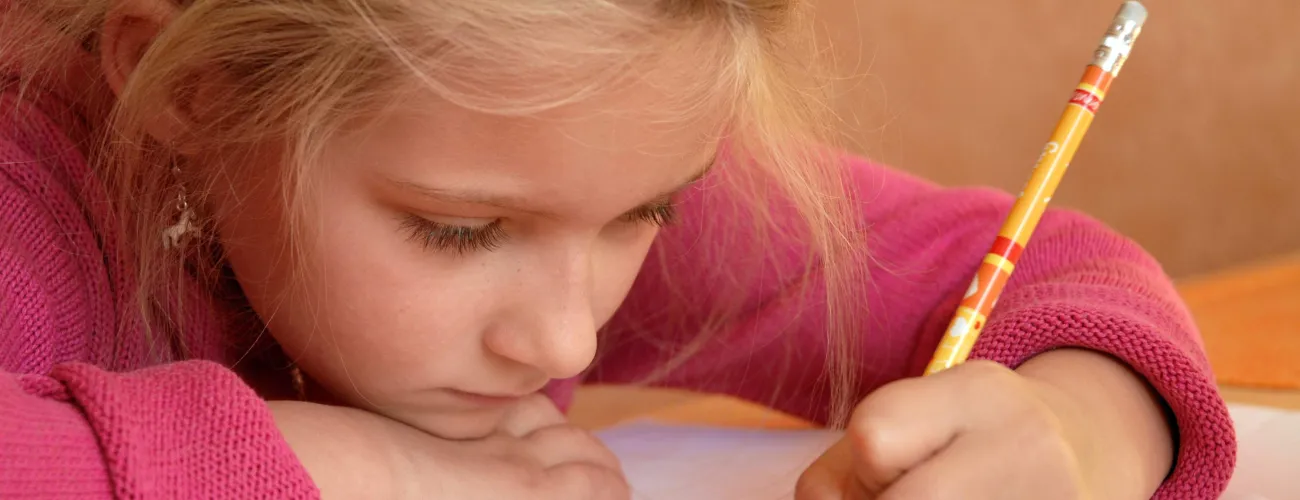 Une petite fille gauchère écrit sur une feuille
