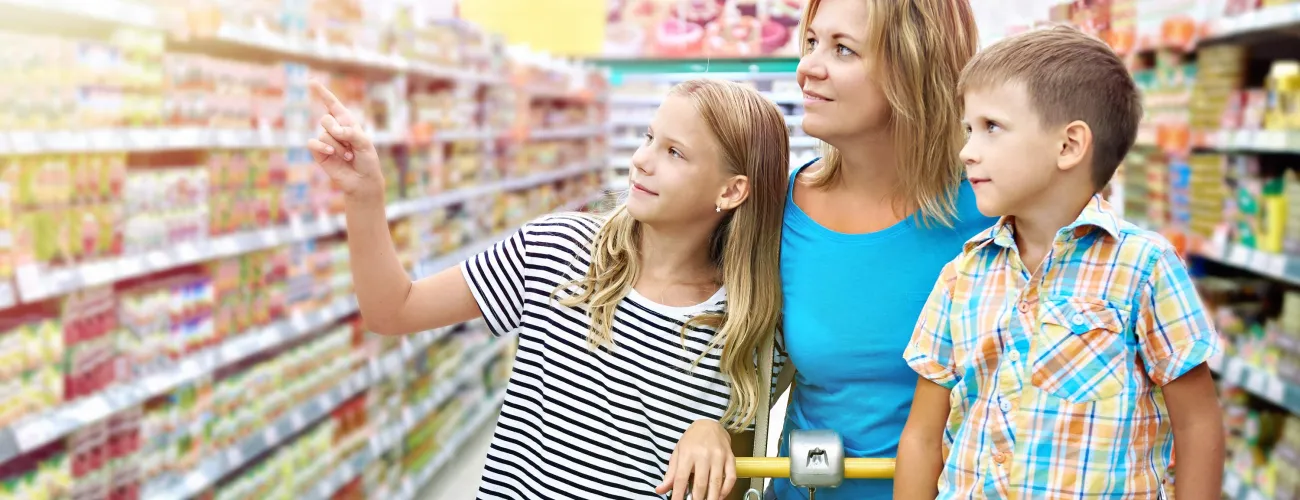 Une femme et ses deux enfants choisissent des produits dans un rayon de supermarché