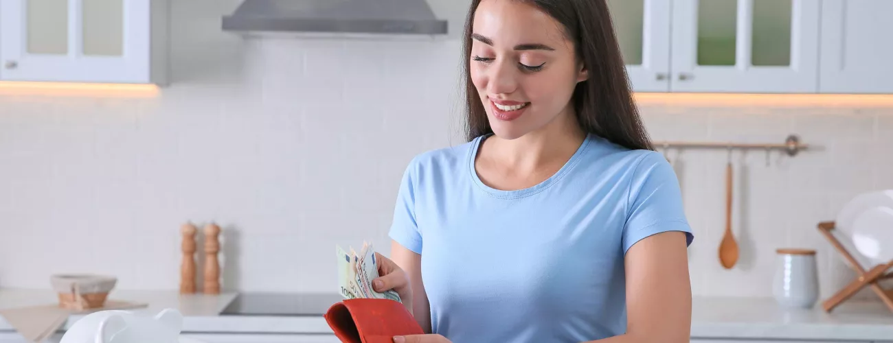 Une femme range des billets dans son portefeuille