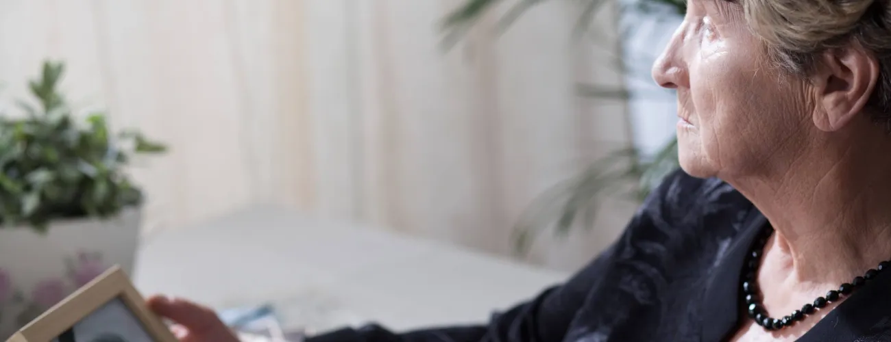 Une dame veuve regarde une photo de son mari décédé
