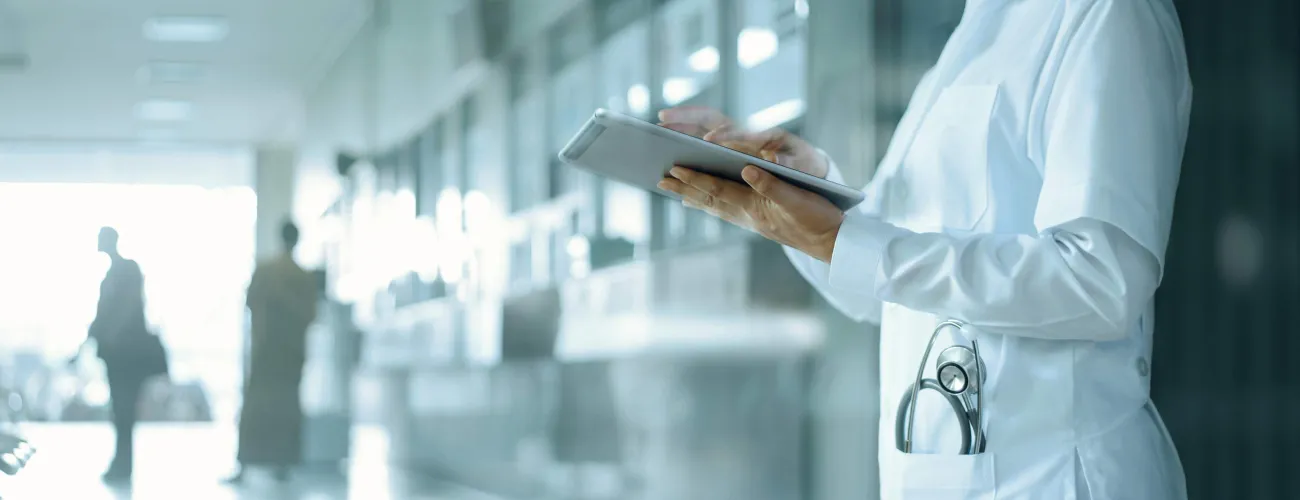 Une prestataire médicale utilise une tablette dans un couloir d'hôpital