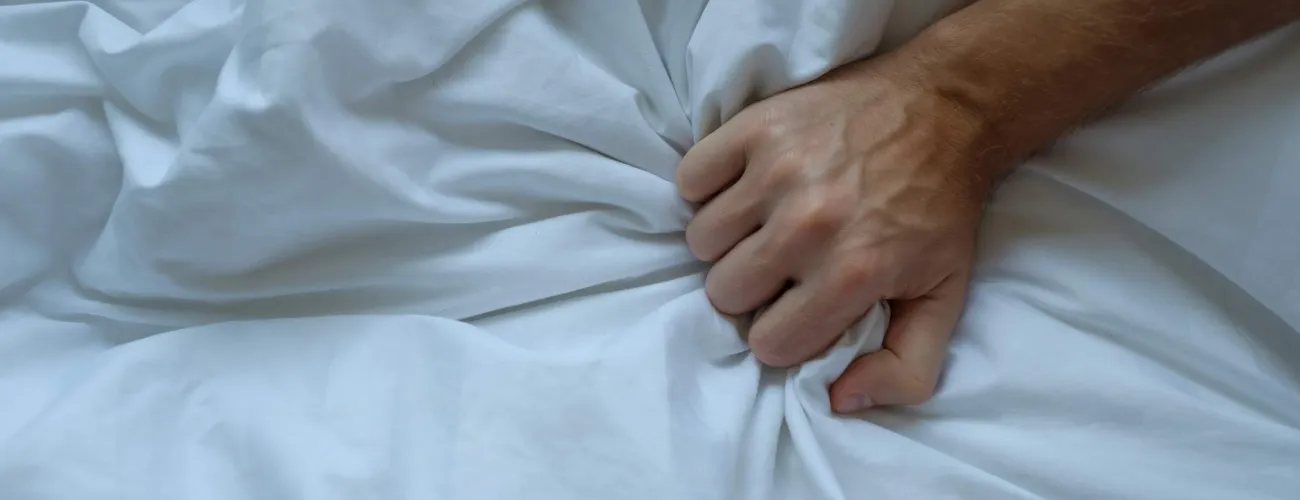 Une main d'homme agrippe une couette blanche