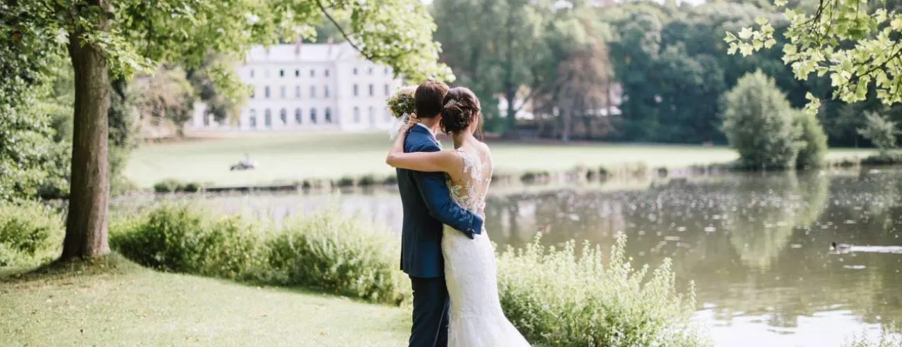 Un coupe marié pose devant un étang