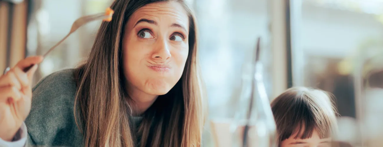 Une femme fait une grimace en observant un morceau de nourriture sur une fourchette