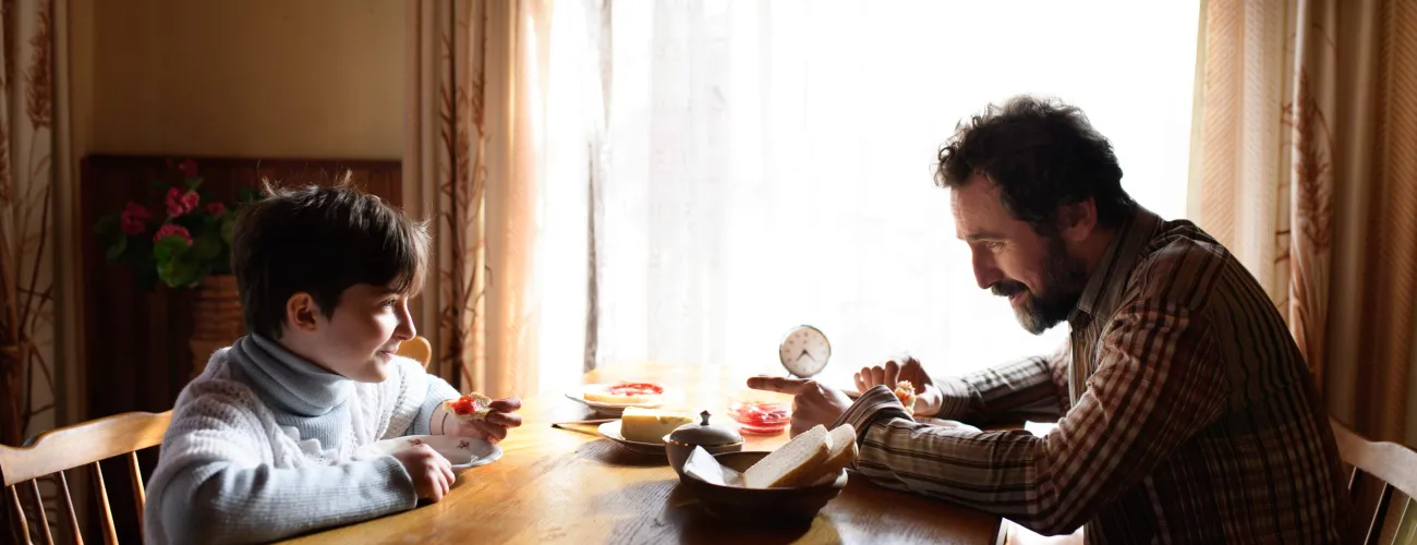 Un père et son fils prennent le petit déjeuner à table