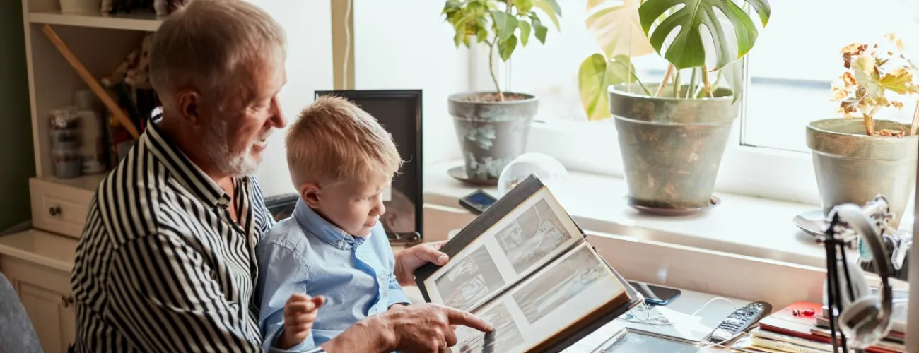 Un grand-père et son petit-fils consultent un album avec des photos de famille