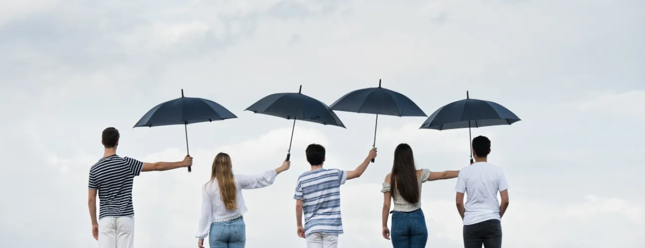 Cinq personnes de dos qui se tiennent un parapluie 