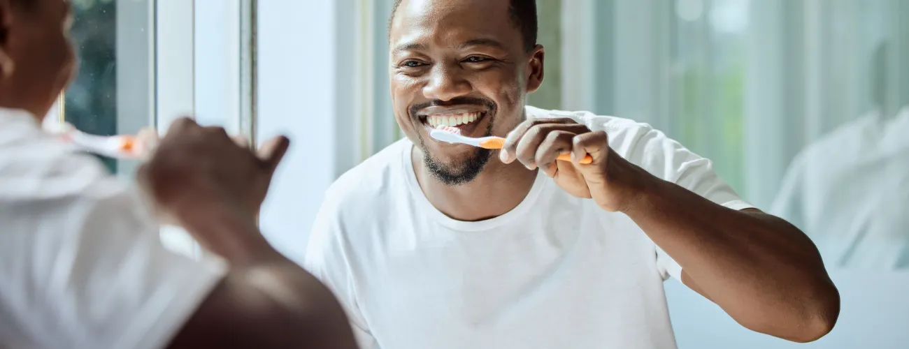 Un homme se brosse les dents devant le miroir