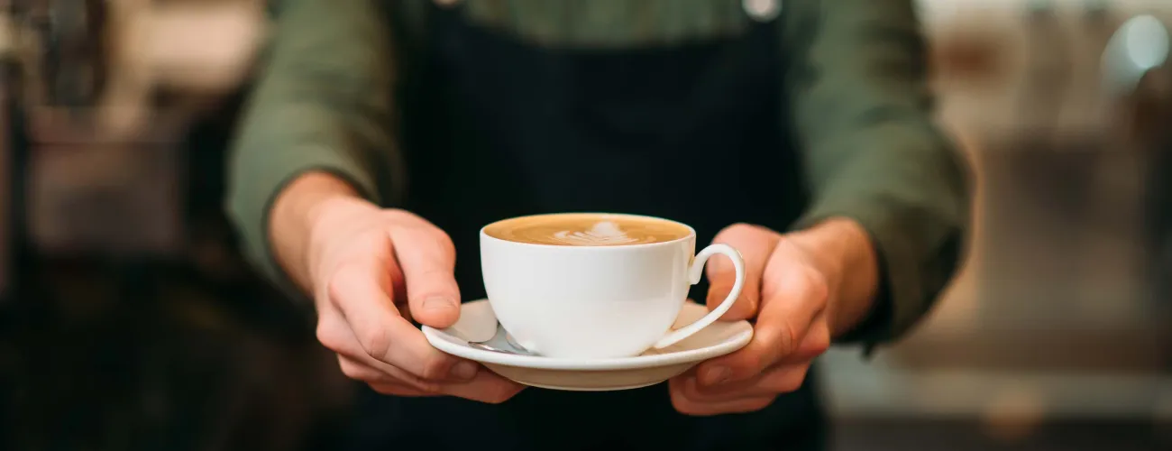 Un barista tend une tasse de café