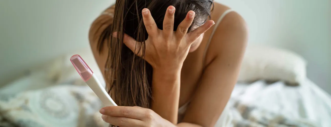 Une femme dépitée tient un test de grossesse en main