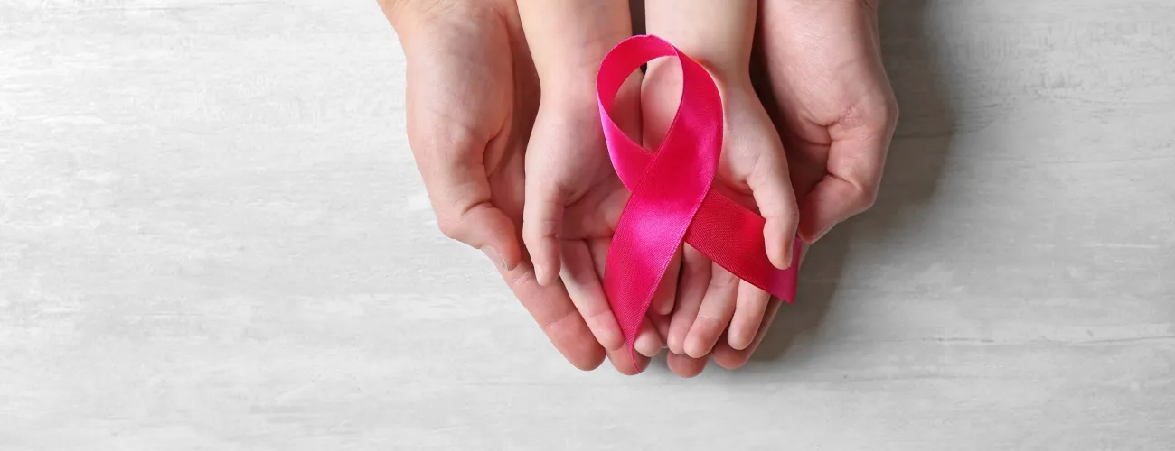 Des mains d'adulte et d'enfant tiennent un ruban rose