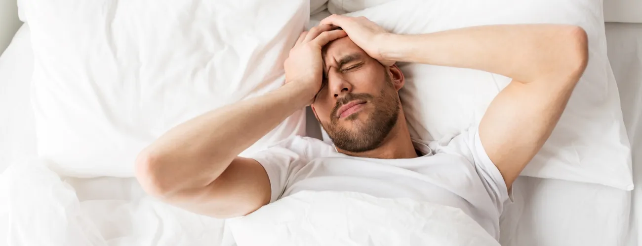 Un homme qui a une insomnie se tient la tête couché dans son lit