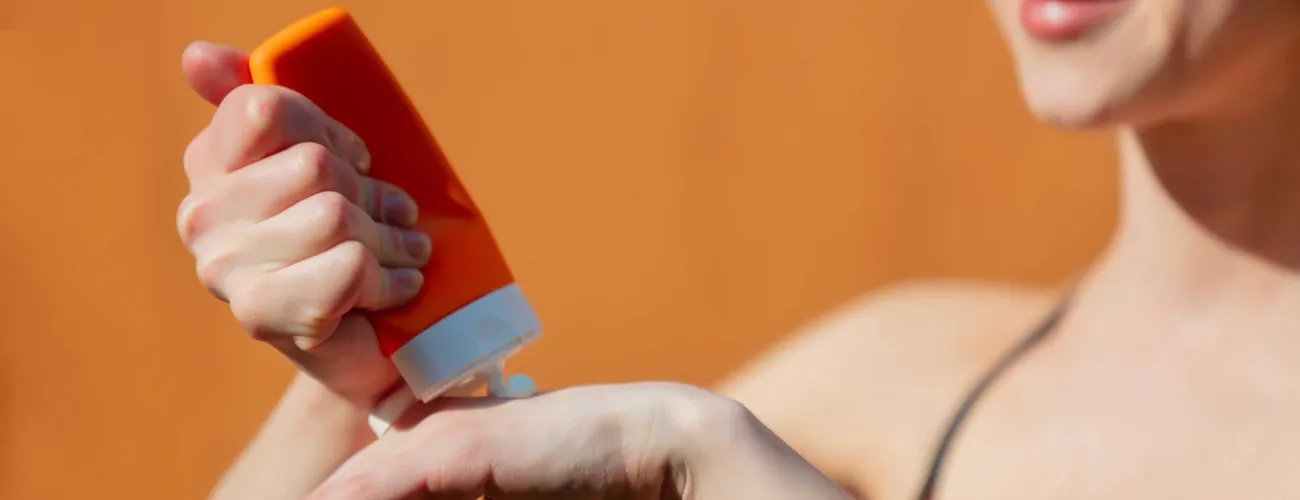 Une femme s'applique de la crème solaire sur la main