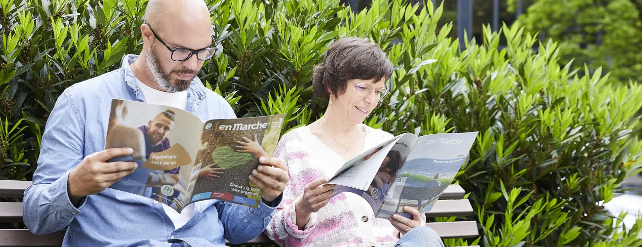 Un homme et une femme lisent le magazine En Marche sur un banc