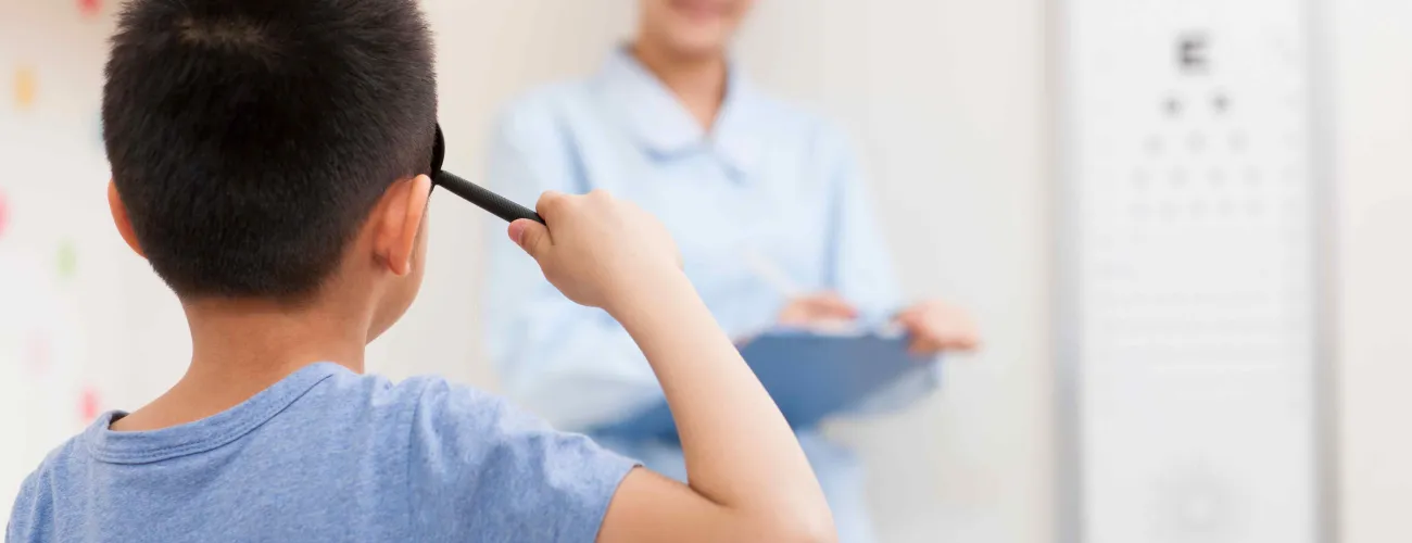 un enfant passe un examen de la vue et déchiffre des lettres au tableau