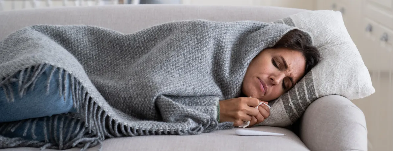 personne malade tenant un thermomètre