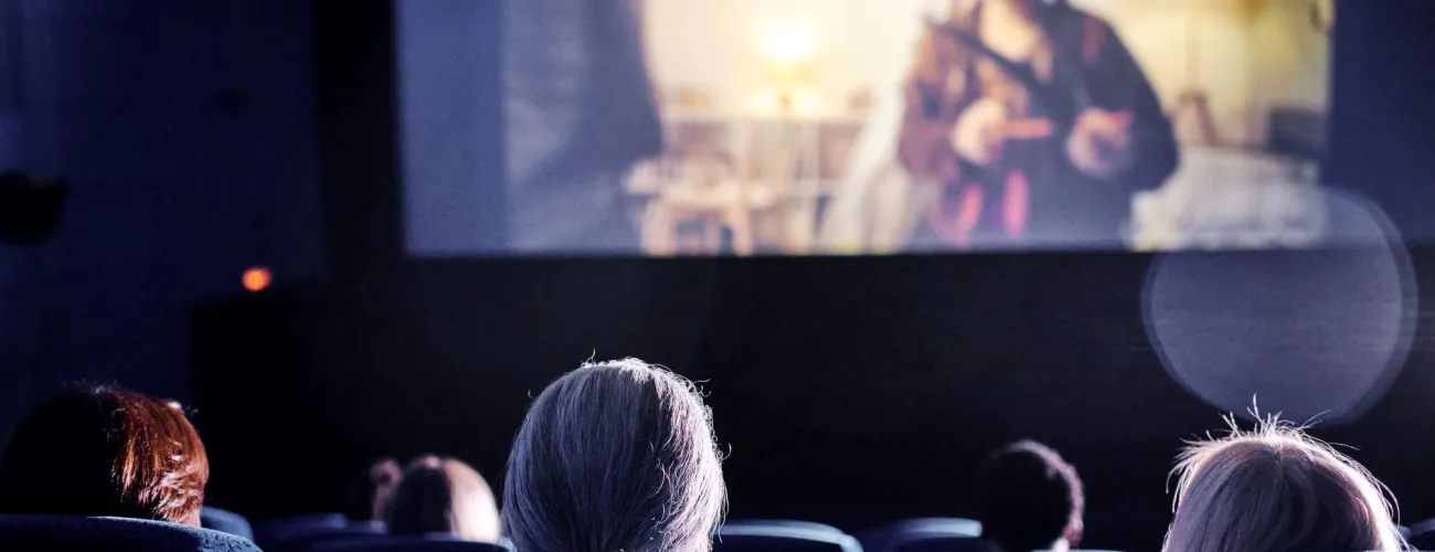 dans une salle de cinéma, on aperçoit des personnes de dos et une partie de l'écran de cinéma