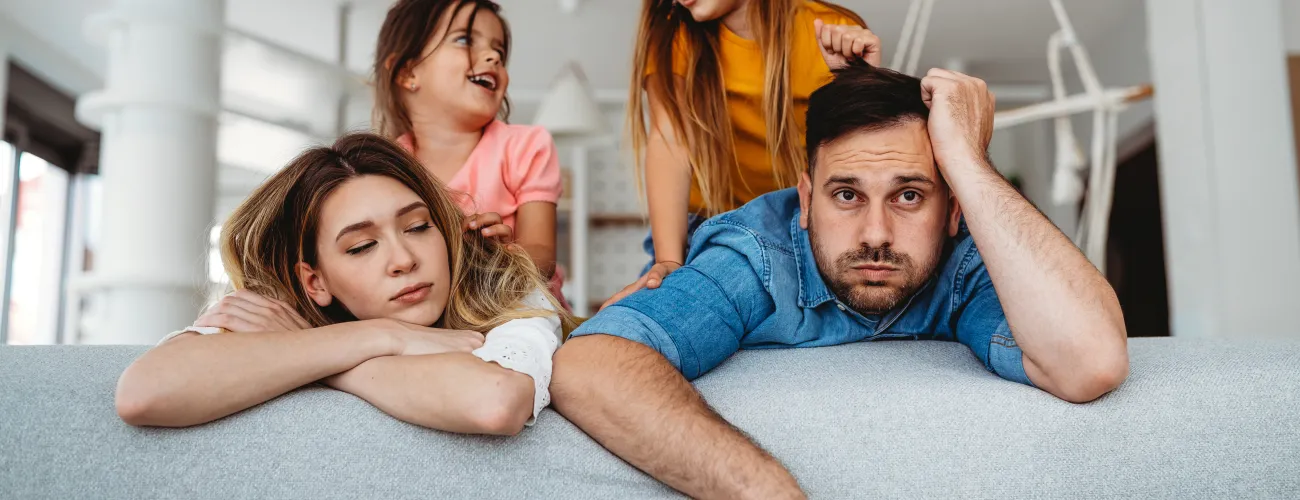 Des parents épuisés par leurs enfants sur un canapé