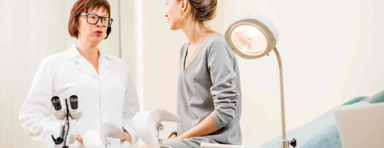 Une jeunne femme assise sur la table d'examen chez la gynécologue