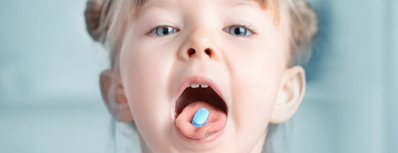 une petite fille a un médicament sur la langue