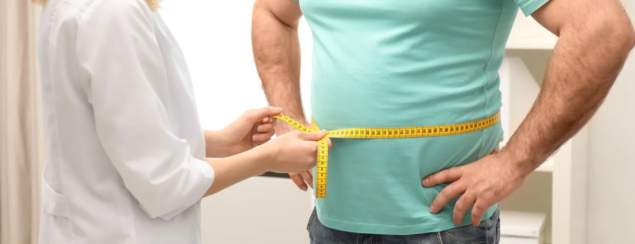 Une médecin mesure le tour de taille d'un patient.