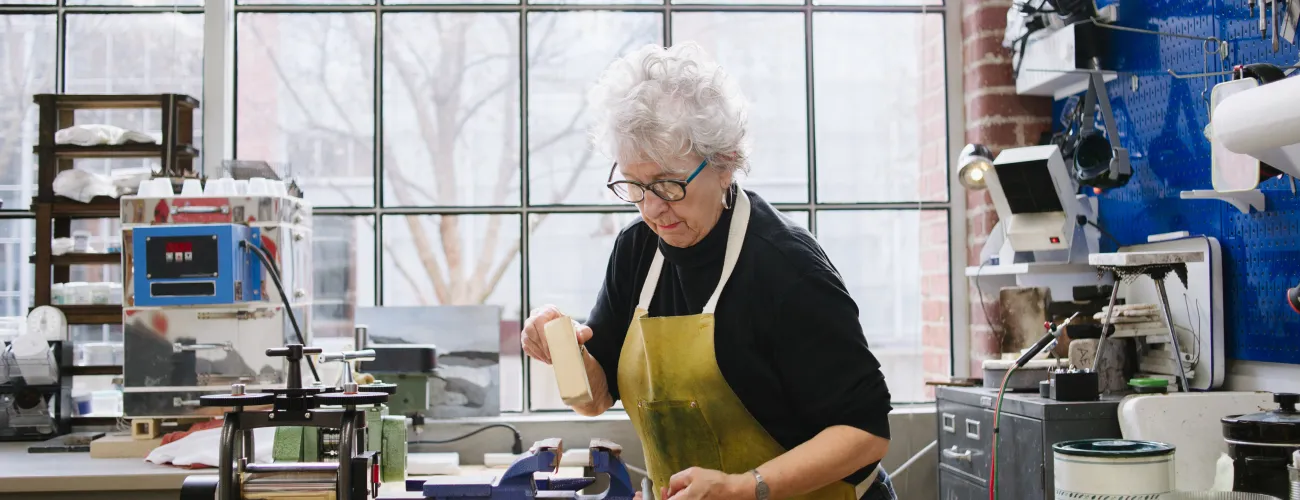 une dame âgée travaille le bois dans un menuiserie