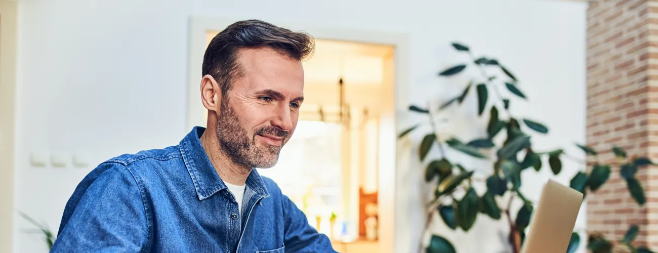 Un homme consulte son ordinateur et sourit