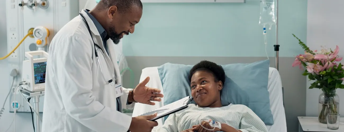 Un médecin donne des informations à une patiente allongée. Les deux personnes sourient. 