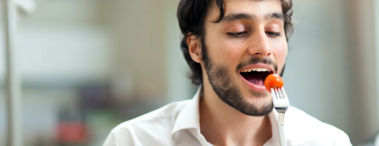 un jeune homme mange une salade
