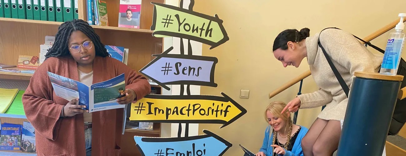 Des jeunes entourent des paneaux de direction qui illustrent les questions d'orientation aux études