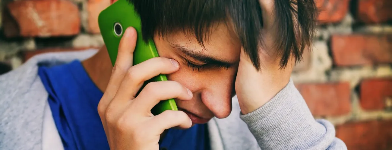 Un jeune homme appelle quelqu'un avec son téléphone.