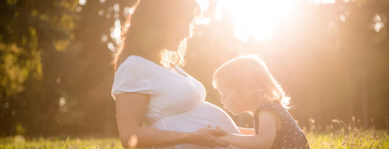 une petite fille embrasse le ventre de sa maman pour protéger la santé du bébé pendant les 1000 jours
