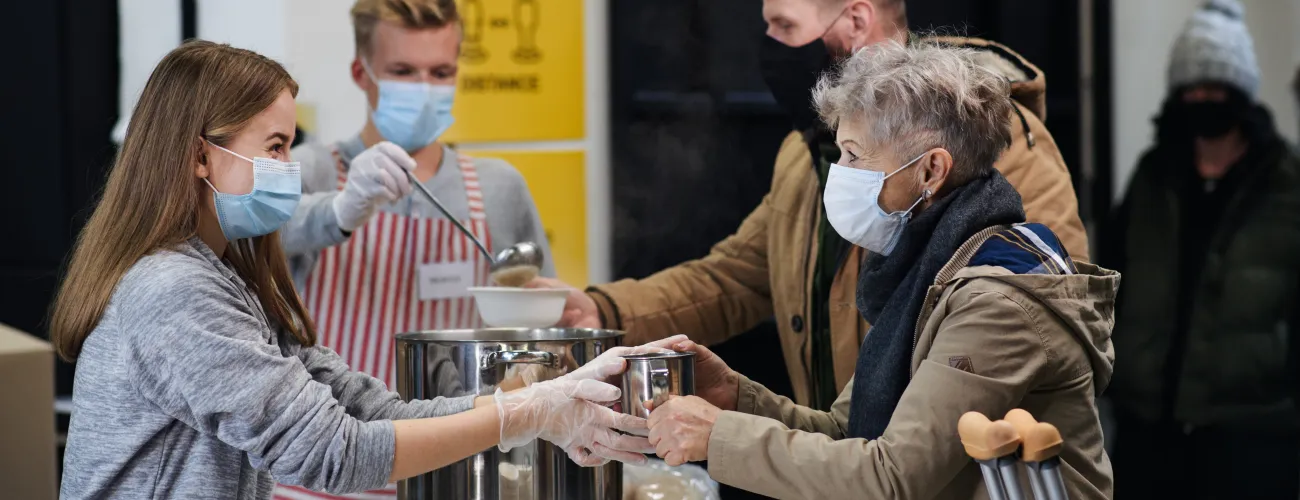 des gens masqués distribuent de la soupe