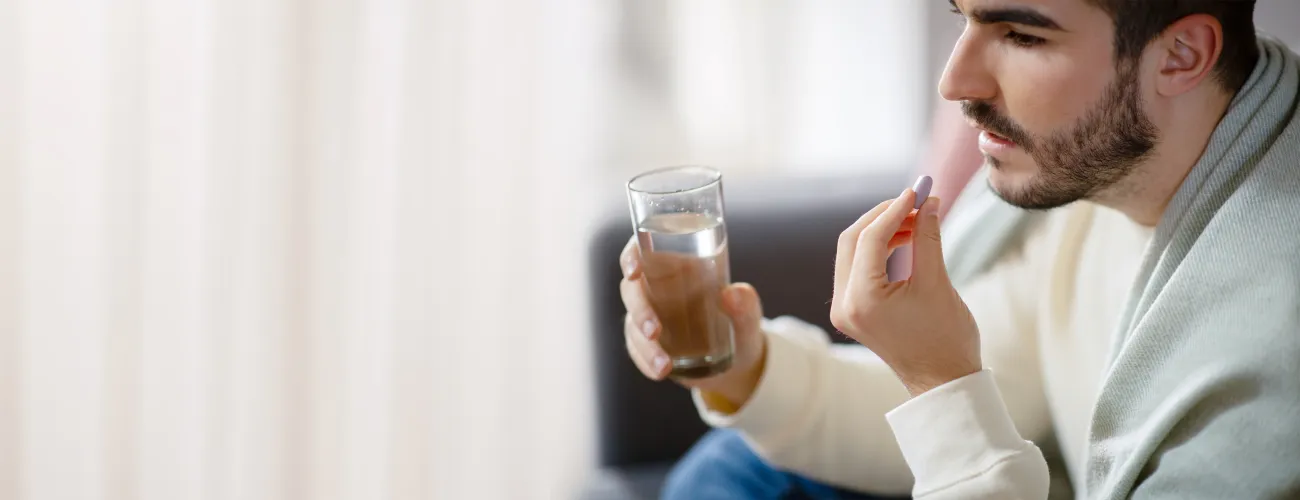 un homme avale un médicament