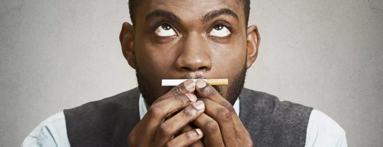 un homme se retient de fumer une cigarette