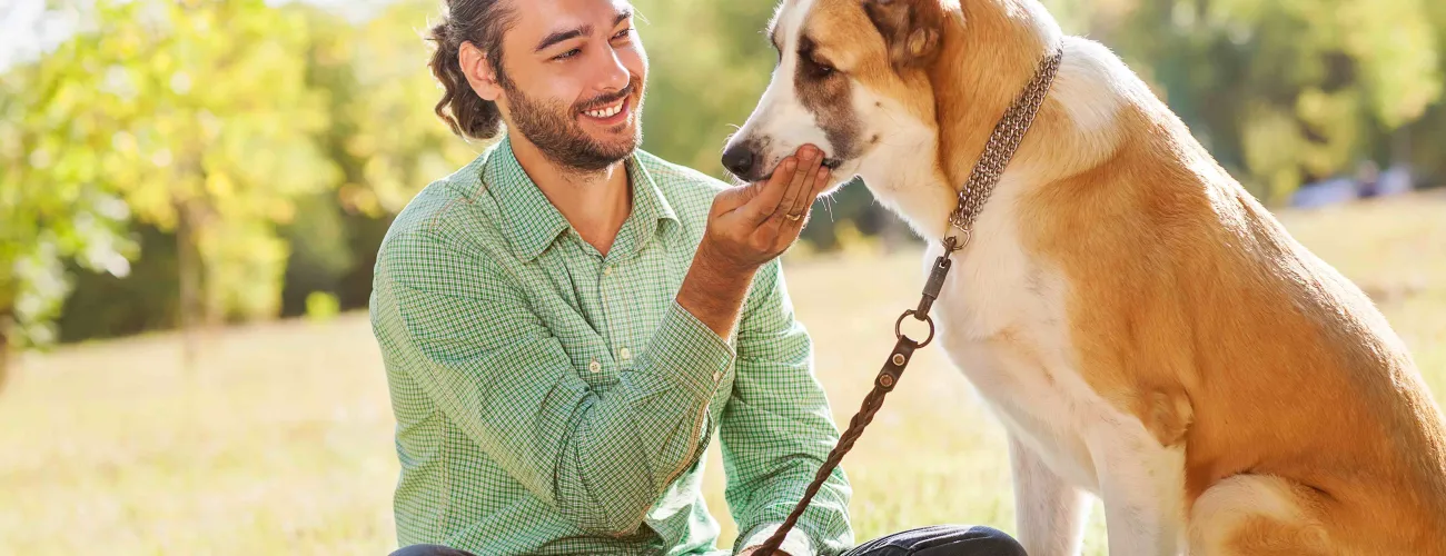 Un homme assis en tailleur caresse son chien assis en face de lui